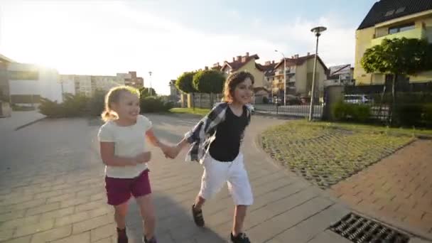 Boy And Girl Run Together Holding Hands On Asphalt. They Have A Lot of Fun. - Кадри, відео