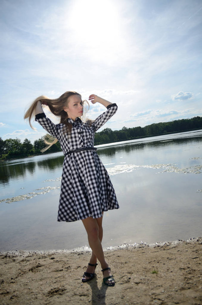 湖で、小柄な女性。水の近くポーズ ブラック ホワイト ドレスで女性モデル. - 写真・画像