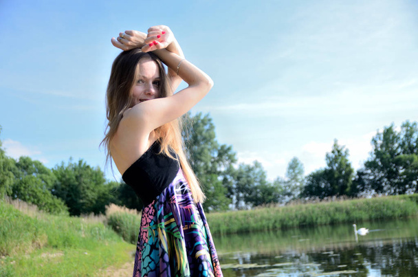 Drobná žena u jezera. Modelka s barevné šaty stojí u vody. - Fotografie, Obrázek