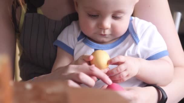 Young Caucasian mother and little son at the festive table eat Easter eggs, slow motion - Materiaali, video