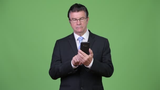 Senior handsome businessman using phone - Filmati, video