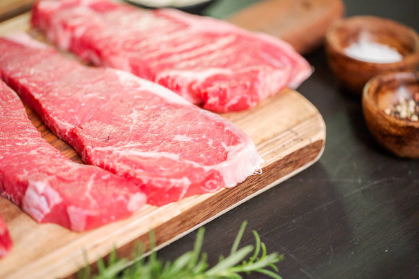rohe New-York-Streifen-Steaks auf einem Holzschneidebrett. - Foto, Bild