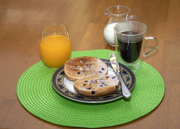 getoastetes Blaubeerbagel-Frühstück mit Kaffee und Orangensaft. - Foto, Bild