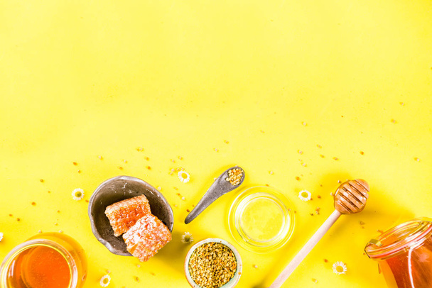 Органический цветочный мед, в банках, с пыльцой и медовыми расческами, с дикими цветами креативной компоновкой ярко-желтый фон
 - Фото, изображение