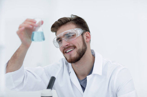closeup. chemist holding a beaker with a solution - 写真・画像