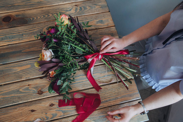 Beautiful bouquet in rustic style with red tape. Collecting the bouquet - Φωτογραφία, εικόνα