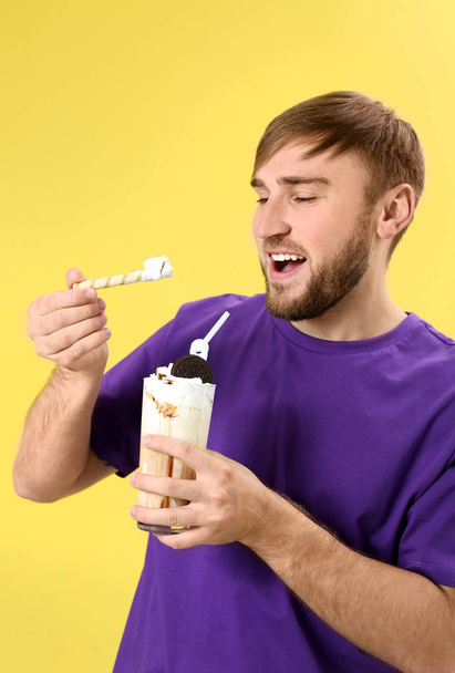 Young man with glass of delicious milk shake on color background - Fotó, kép