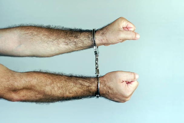 Yakın çekim. Tutuklanan adam elleri kelepçeli. Mahkum veya tutuklanan terörist, elleri kelepçeli yakın çekim - Fotoğraf, Görsel