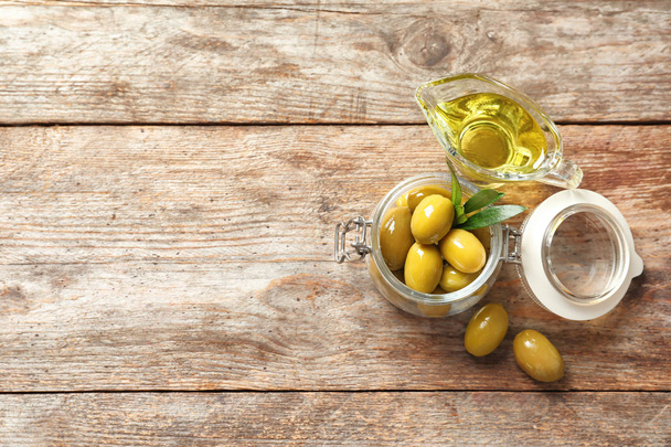 Beautiful composition with oil and ripe olives on wooden table, top view - 写真・画像