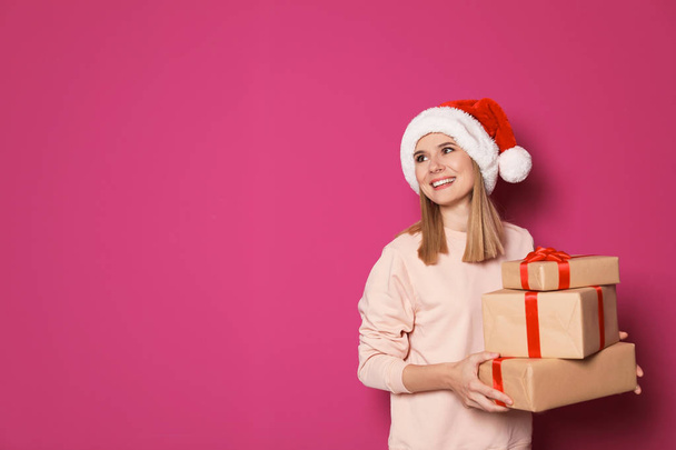 Young woman with Christmas gifts on color background - Fotó, kép