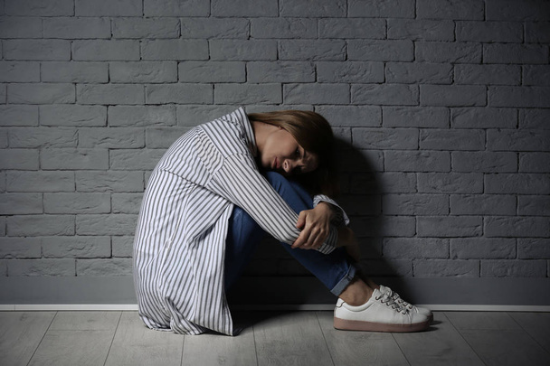 Lonely woman suffering from depression near brick wall - Foto, Imagem