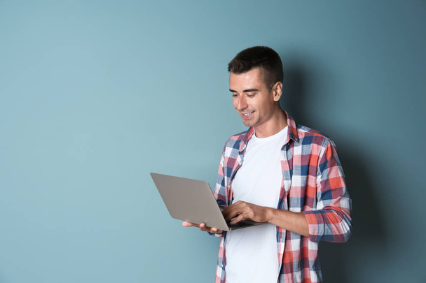 Man in casual clothes with laptop on color background - Foto, afbeelding