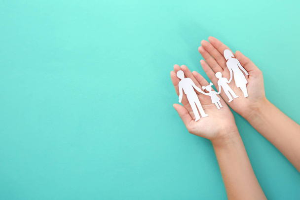 Woman holding paper family cutout on color background, top view - Φωτογραφία, εικόνα