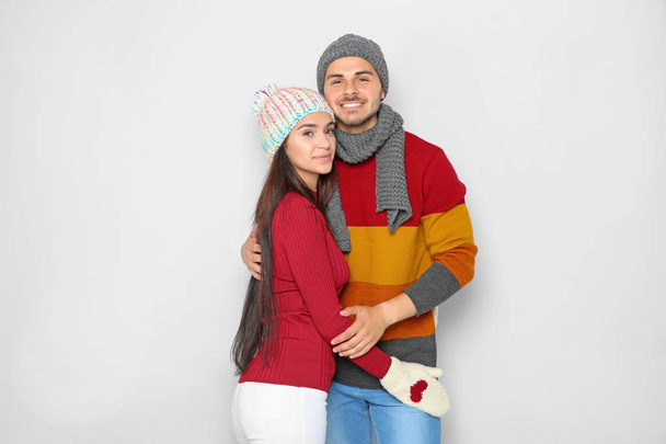Young happy couple in warm clothes on light background. Christmas celebration - Photo, Image