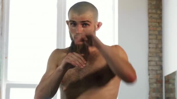 Bearded professional male kickboxer shadowboxing at sports studio - Filmati, video