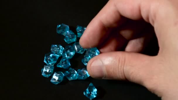 Mężczyzna ręcznie sprawdzić jakość niebieskie diamenty lub kamień na czarnym tle. Kamienie są surowe i nie szczotkowanej. Zbliżenie, Selektywny fokus - Materiał filmowy, wideo