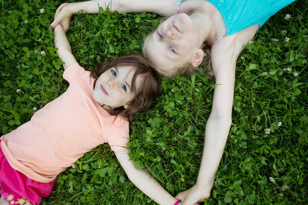 niñas sonrientes novias en la hierba verde. vacaciones infantiles
 - Foto, imagen