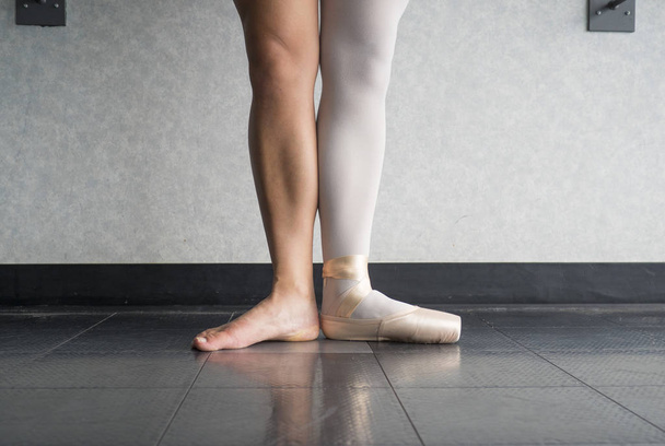 zwei Seiten zu einer Ballerina, ein Bein trägt ihren Ballettschuh Spitzenschuh auf einem Fuß und ein Bein entblößt - Foto, Bild