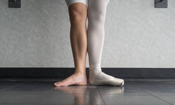 Balett-táncos első pozícióban egy lábbal a Pointe cipő, és egy csupasz láb - Fotó, kép