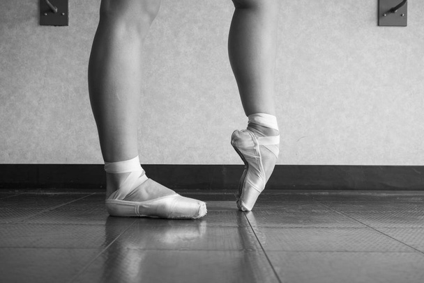 Version noire et blanche de Ballerina réchauffant ses pieds dans ses chaussures de ballet pointe avant le cours
 - Photo, image