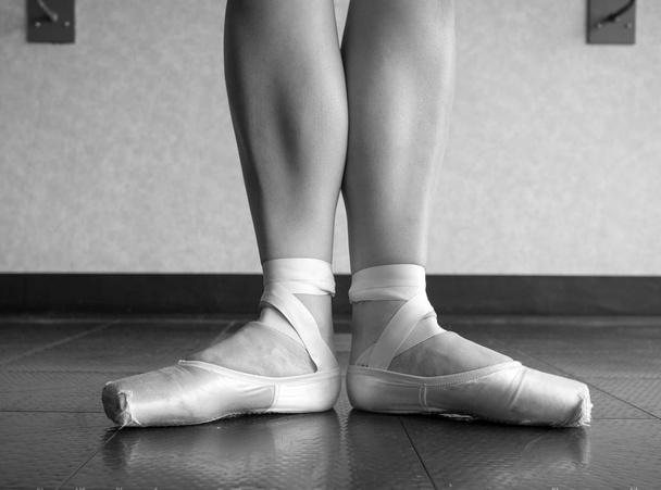 Black and White version of Ballerina in Ballet first position in ballet pointe shoes and bare legs - Photo, Image