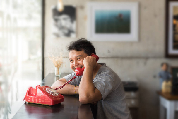 asiatico uomo 40 in grigio t-shirt felice sorriso e amore tra parlare telefono chiamata da amante in un caffè caffè con un rosso telefono vintage stile
 - Foto, immagini