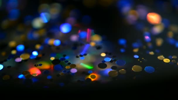 Desfocado cintilante multicolorido glitter confetti, fundo preto. Férias abstrato festivo bokeh pontos de luz
. - Filmagem, Vídeo