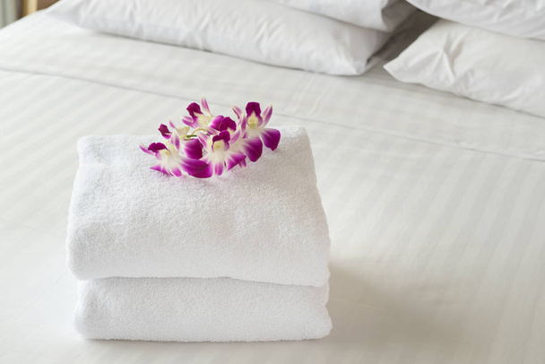 Κοντινό πλάνο, Λευκή πετσέτα με λουλούδια τοποθετημένα στο εσωτερικό του δωματίου του ξενοδοχείου. - Φωτογραφία, εικόνα