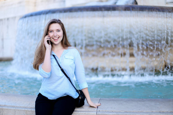 junge Frau spricht mit Smartphone im Hintergrund des Trevi-Brunnens. - Foto, Bild