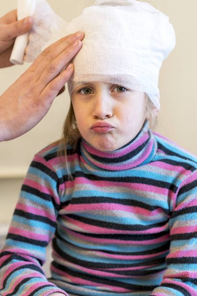 Docteur fait un bandage de la tête de la jeune fille après la chirurgie plastique. photo verticale
. - Photo, image