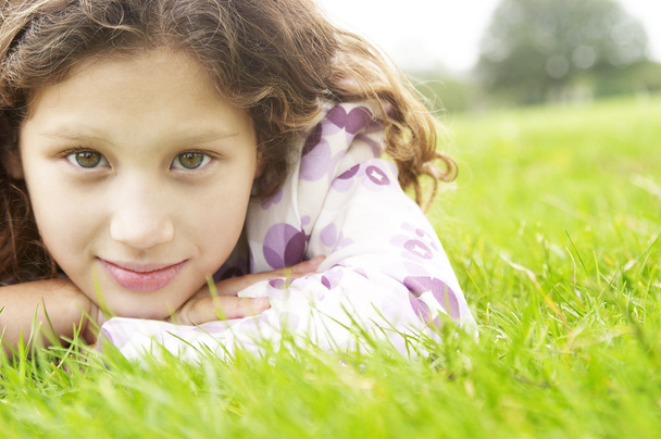 portret młodej dziewczyny, ustanawiające na zielonej trawie w parku. - Zdjęcie, obraz