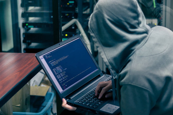 Hacker organisieren massiven Datendiebstahl auf Unternehmensservern. Er hält sich an einem geheimen Ort auf. ihr Versteck ist dunkel, neonbeleuchtet, Serverraum - Foto, Bild