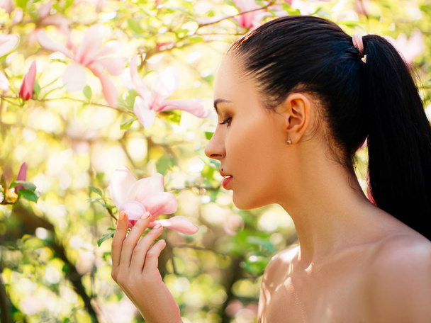 Tavasszal virágzó magnólia kert pózol a gyönyörű fiatal nő portréja - Fotó, kép