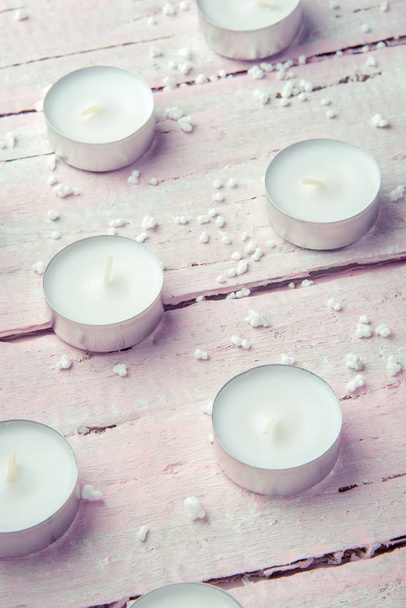 Een paar platte witte kaarsen op een mooie roze houten tafel - Foto, afbeelding