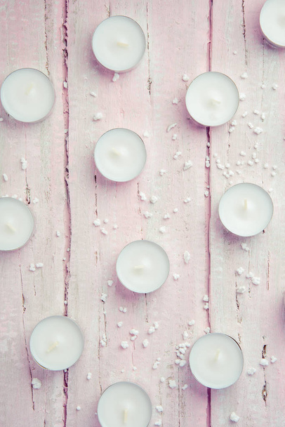Een paar platte witte kaarsen op een mooie roze houten tafel - Foto, afbeelding