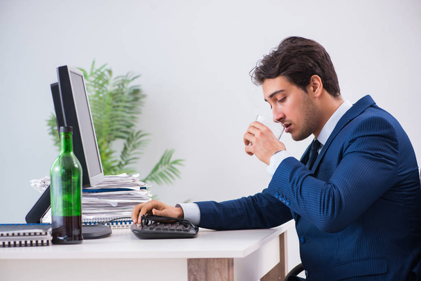 Young businessman employee drinking in the office at desk - Foto, imagen