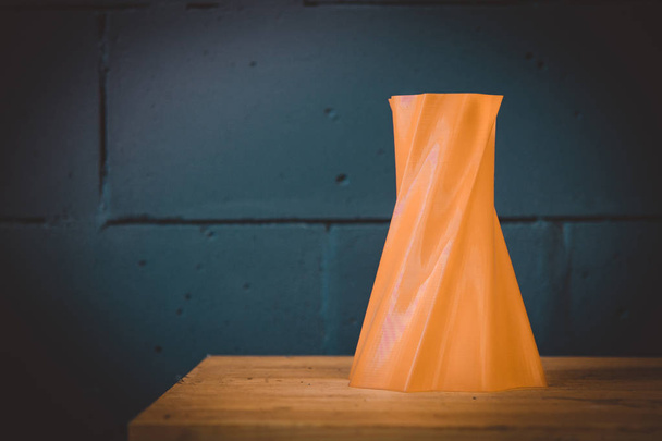 Vase objet rouge brillant imprimé par imprimante 3D sur mur de briques bleues - Photo, image