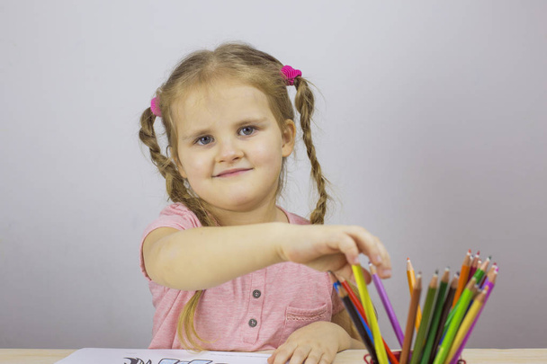 Young girl with colorful pencils looking at the camera - 写真・画像