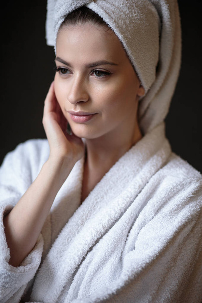 Mujer joven con albornoz y toalla en la cabeza, spa y retrato de cuidado, cara natural limpia
 - Foto, Imagen