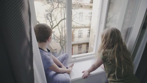 Two young children watching through a window - Кадры, видео