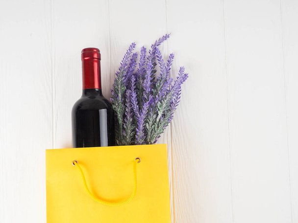 botella de vino y flores en el paquete sobre fondo de madera, espacio para el texto
. - Foto, Imagen