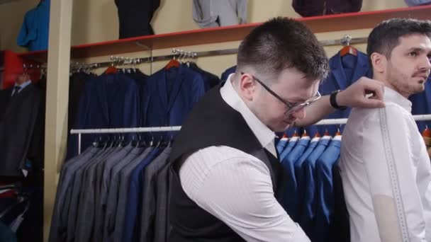 Mann hilft im Bekleidungsgeschäft beim Anprobieren eines Anzugs - Filmmaterial, Video
