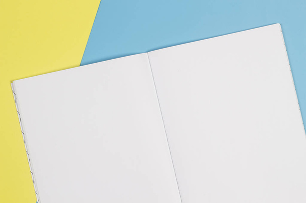 Ανοίξτε το σημειωματάριο και πολύχρωμο σημειωματάρια σε μπλε και κίτρινο φόντο - Φωτογραφία, εικόνα