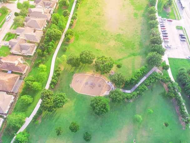 Vista aerea ampio parco giochi vicino al quartiere residenziale di Harwin Park a Houston, Texas. Vista elevata di scivoli e altalene nel parco circondato da alberi verdi, prato erboso e sentiero pedonale
 - Foto, immagini