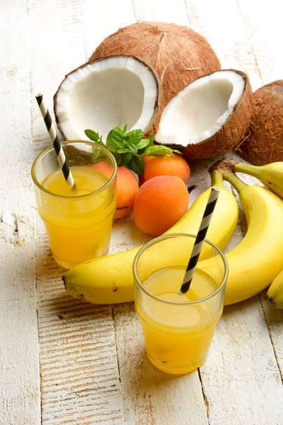 tropical fruits drink with around coconut, bananas and apricots - closeup - Фото, зображення
