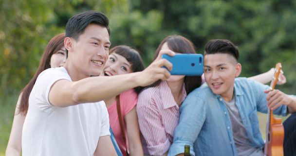 Friends go picnic together in the park and take photo selfie with mobile phone - Valokuva, kuva