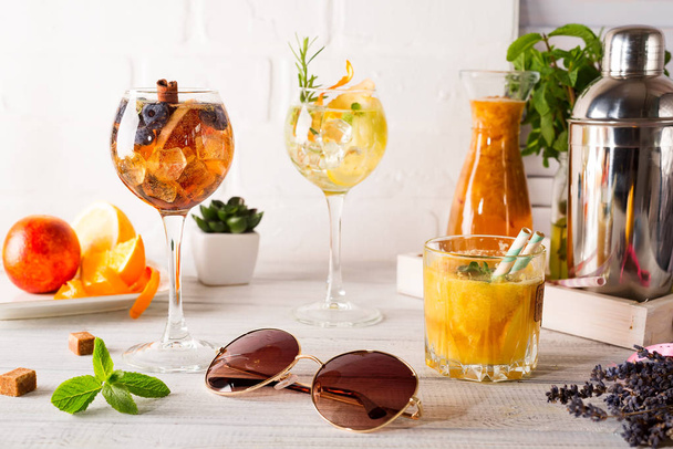 verschiedene alkoholische Getränke im Glas, Rebujito-Cocktail - Weißwein, kohlensäurehaltiges Wasser (Soda), Minze, Zitronensaft mit Früchten auf weißem Holzgrund mit Sonnenbrille - Foto, Bild