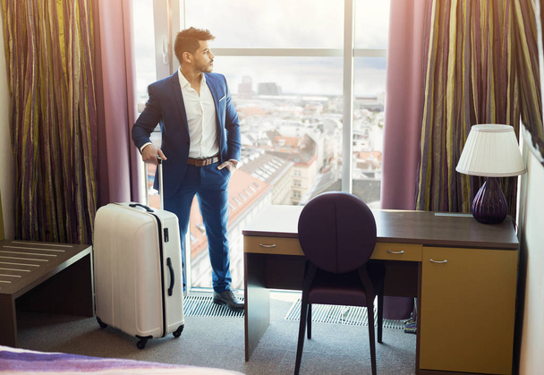 Nuori liikemies matkatavaroiden kanssa hotellihuoneessa
 - Valokuva, kuva