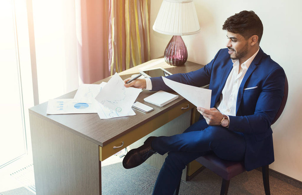 Бизнесмен, работающий с документами в гостиничном номере
 - Фото, изображение