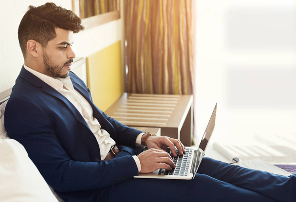 Arabe homme d'affaires couché sur le lit à l'hôtel et utilisant un ordinateur portable
 - Photo, image